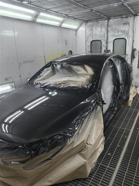 Тёмный автомобиль с замаскированными окнами в окрасочной камере