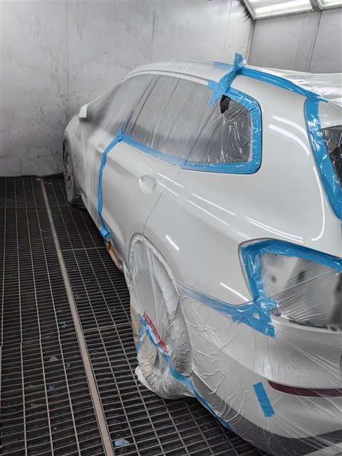 Окрашенное заднее крыло белого автомобиля в камере